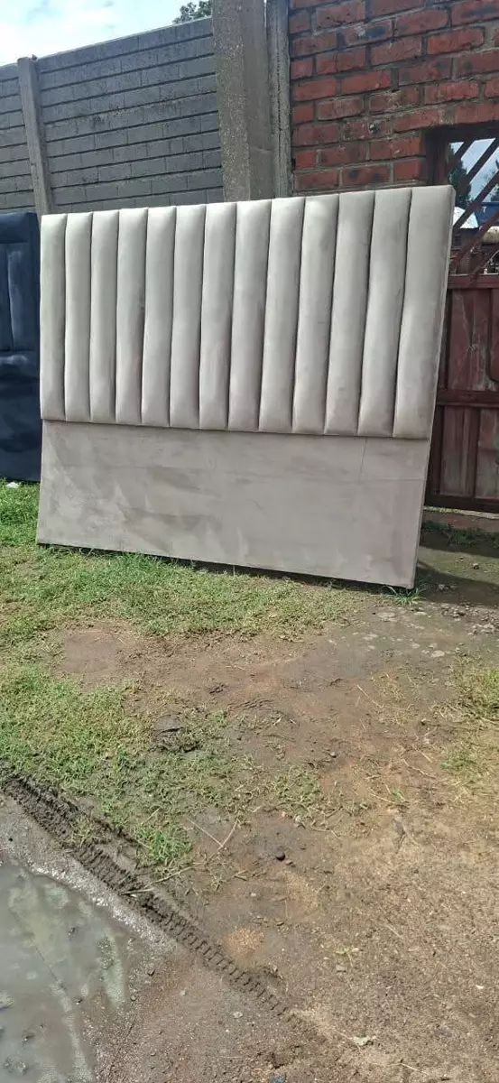 Upholstered headboard standing outdoors on grass against a brick wall